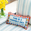 Needlepoint pillow by Furbish brand with bright colors and phrase 'this is a horrible idea what time should I be there' on a striped chair