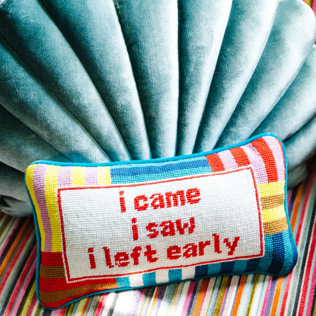 Needlepoint pillow by Furbish brand with bright colors and phrase 'I came I saw I left early' on a striped cushion