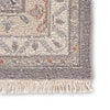 Close up of Jaipur wool JAIMAK rug with Pops of gold and dusty pink on gray backdrop with classic fringe