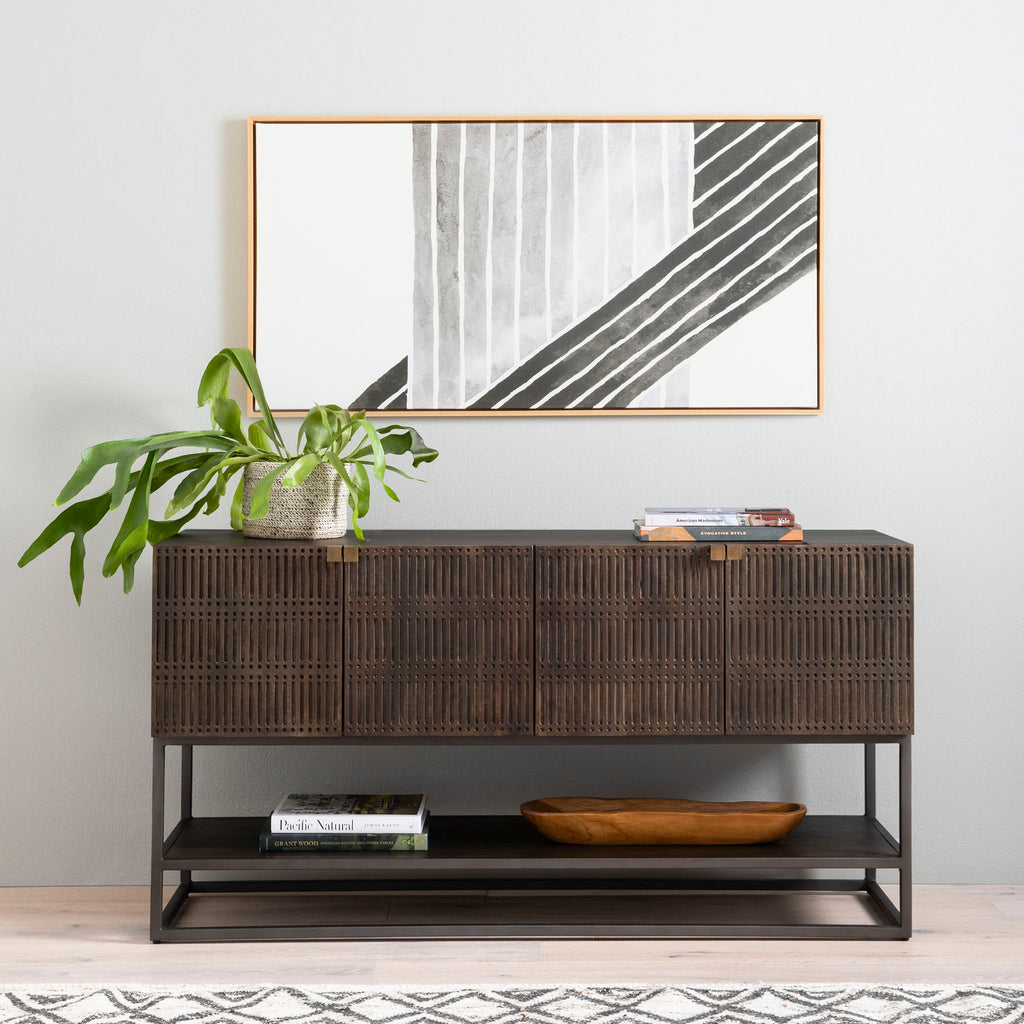 Four hands furniture brand Kelby media console with iron base and four carved doors with square brass pulls on a white background