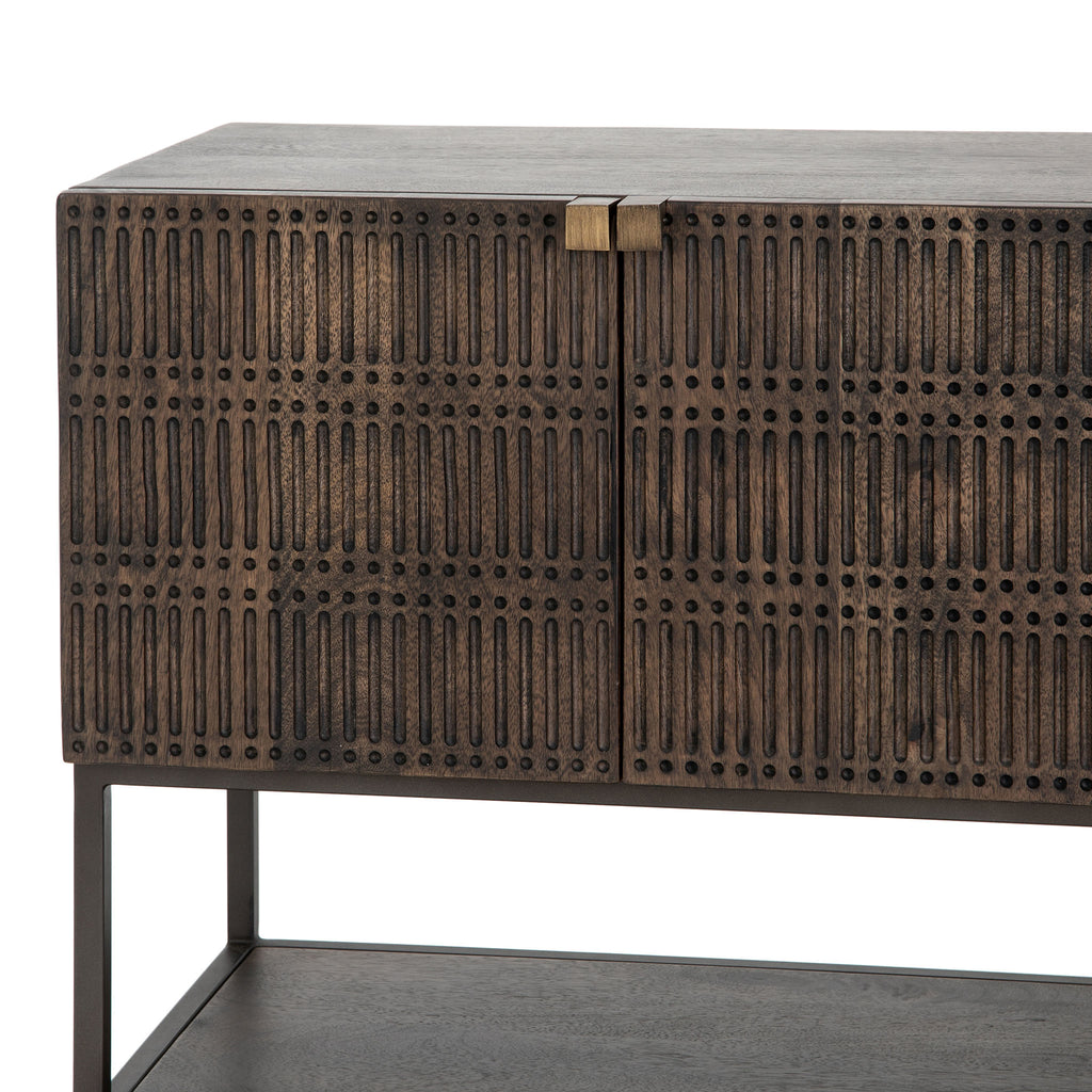 Four hands furniture brand Kelby media console with iron base and four carved doors with square brass pulls on a white background