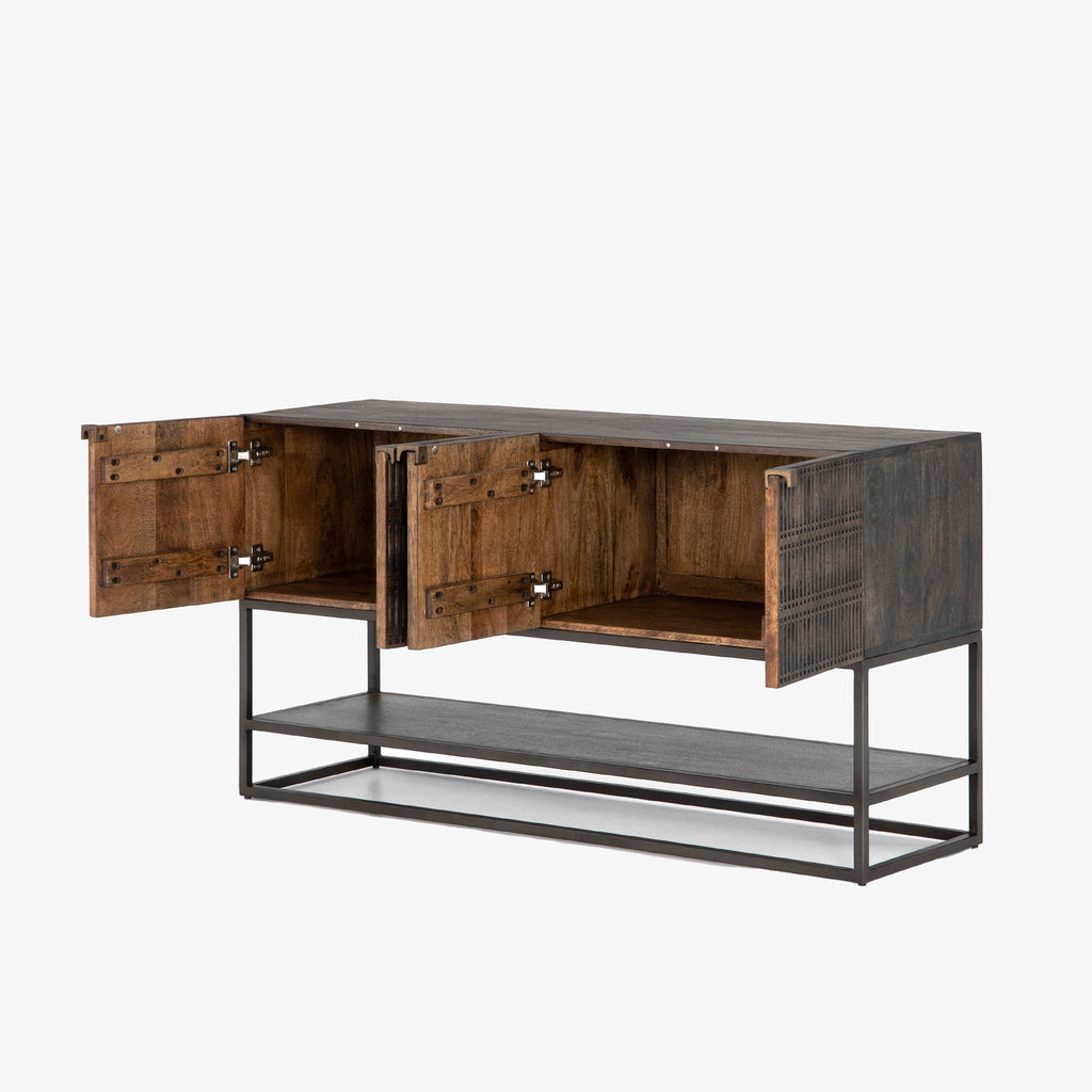Four hands furniture brand Kelby media console with iron base and four carved doors with square brass pulls on a white background