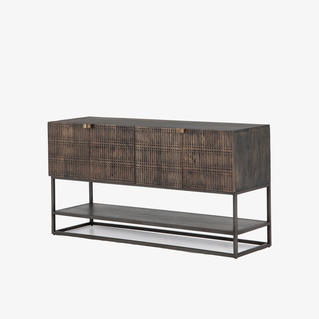 Four hands furniture brand Kelby media console with iron base and four carved doors with square brass pulls on a white background