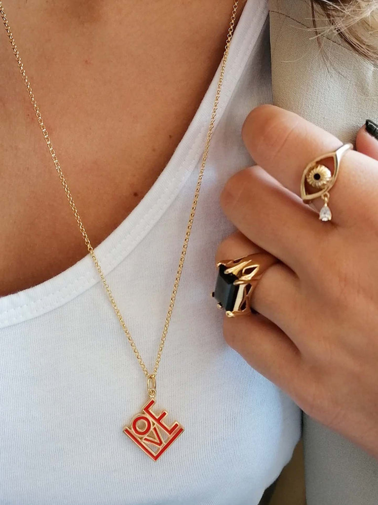 Scream Pretty brand gold love charm on a model with a white white shirt