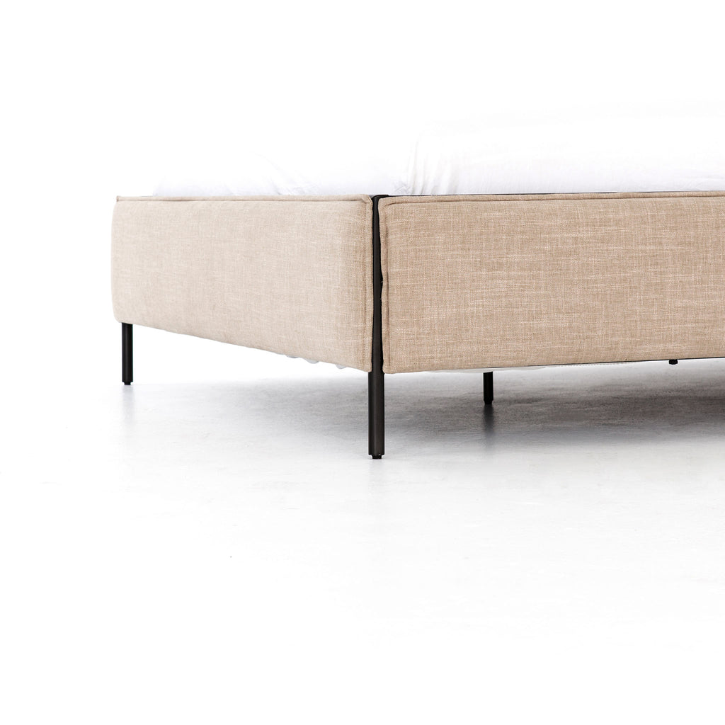 Upholstered 'Leigh' bed by Four hands furniture with metal frame and buckled head board panels on a white background