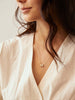 Able brand charm letter necklace worn by a woman with v-neck white shirt 