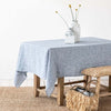 Light blue linen tablecloth on a table with sisal rug and bench