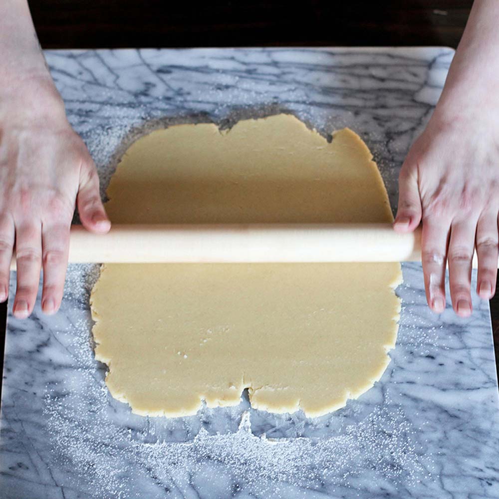 JK Adams lovely rolling pin on a marble surface with hands rolling out dough