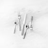 Stainless flatware five piece set with simple lines and polished finish on a marble surface