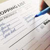 Hand with pen writing on market shopping list 