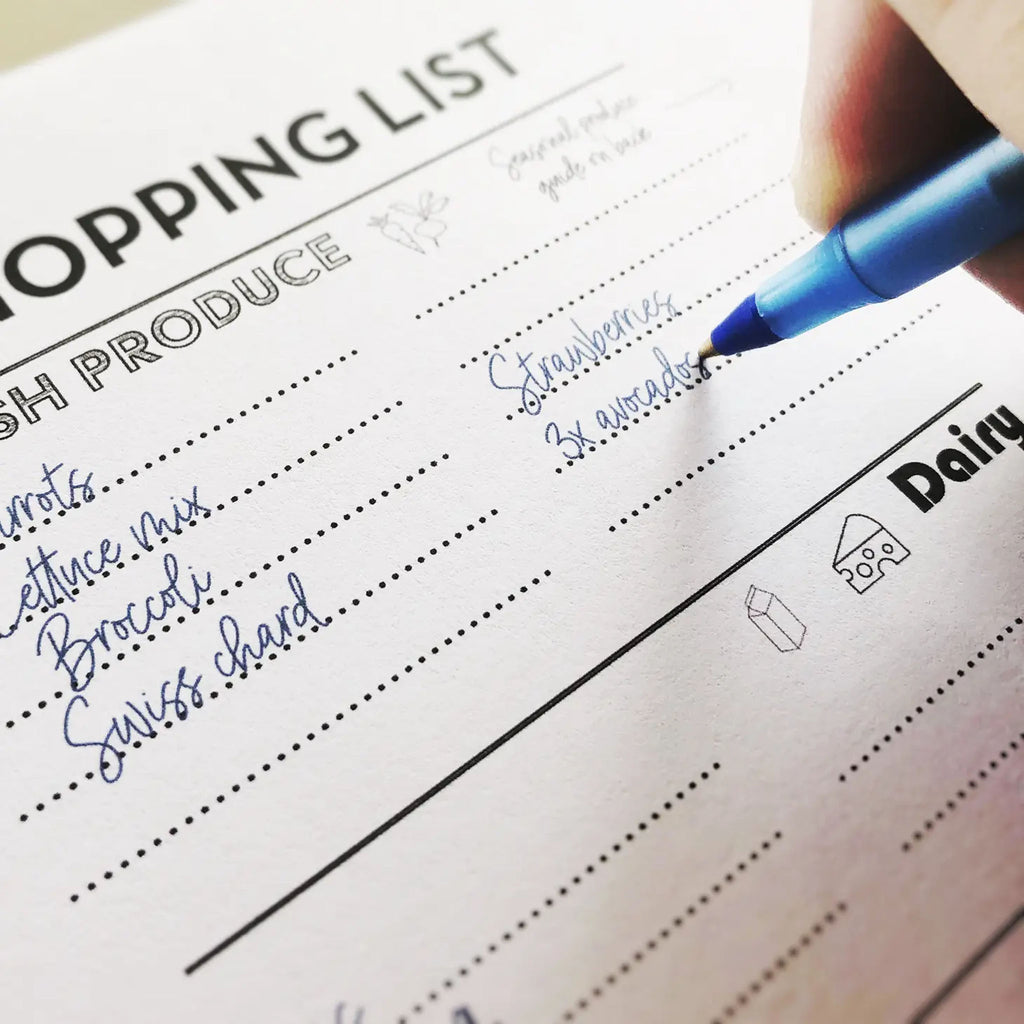 Hand with pen writing on market shopping list 