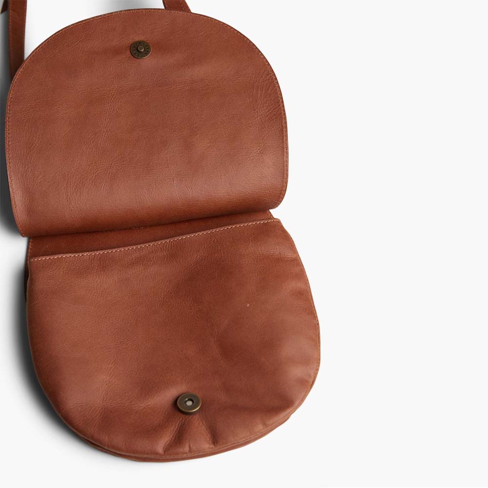 Able brand Martha saddle bag opened in whiskey color with adjustable shoulder strap on a white background