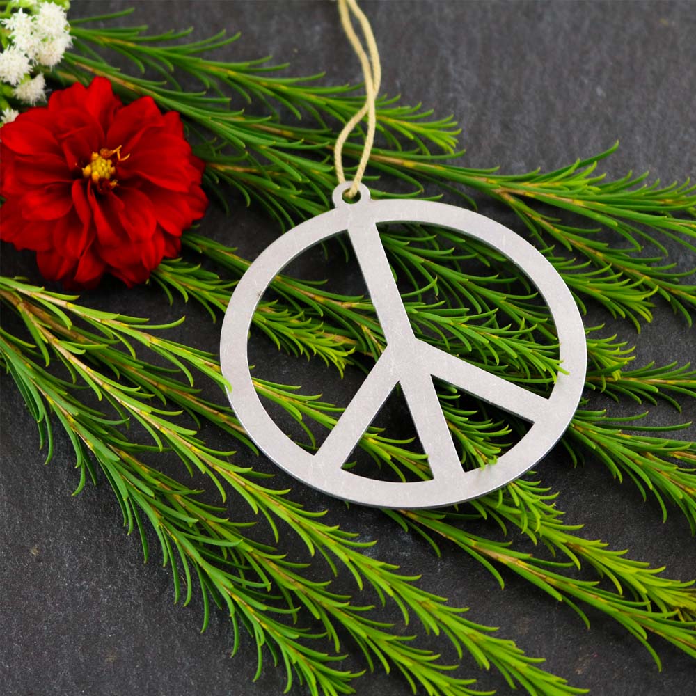 Brushed aluminum metal peace sign ornament on a green background