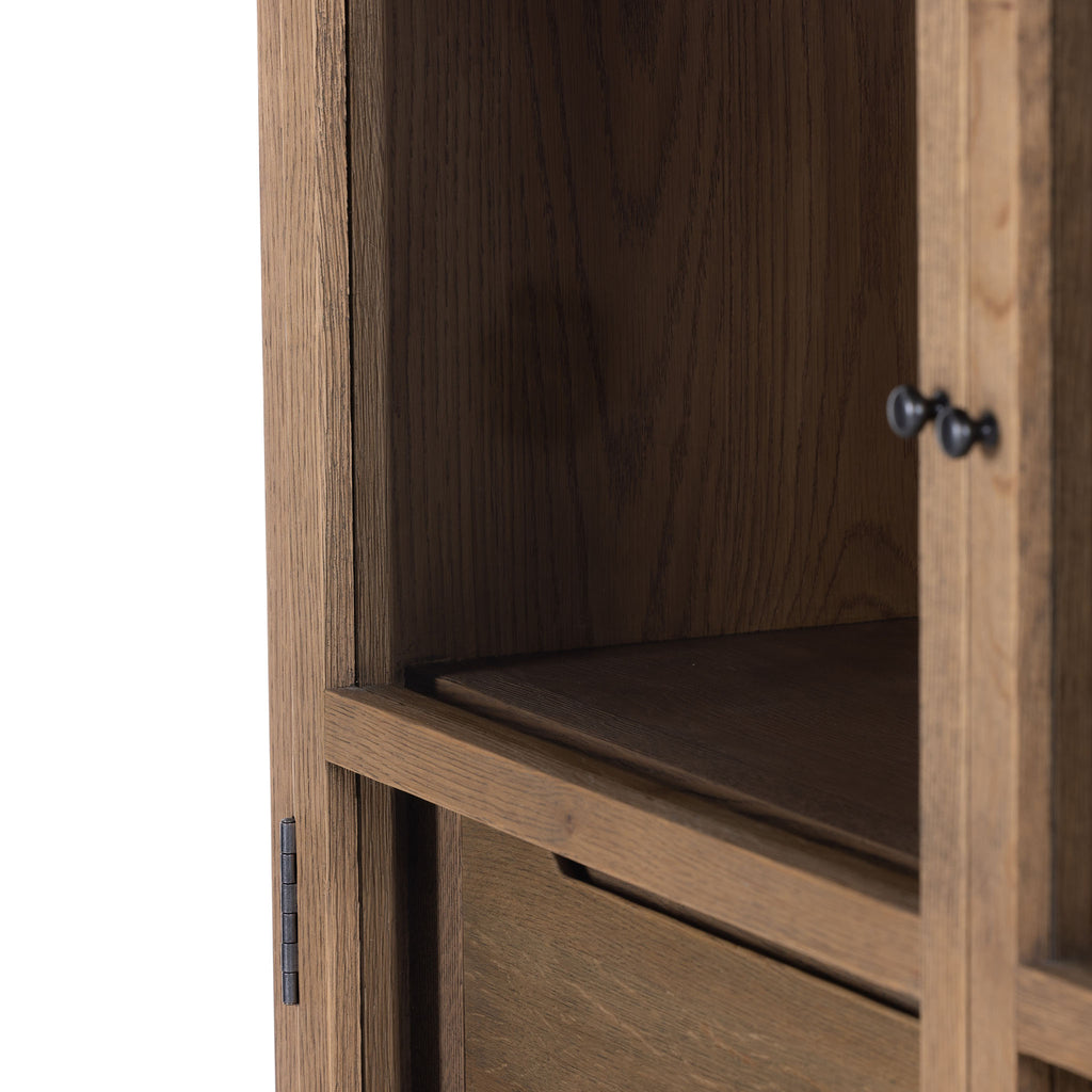 Close up of knobs on Four hands furniture brand Millie oak cabinet with glass doors and four shelves and interior drawer on a white background