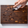 Wood board with droplets of mineral oil and hand with bottle
