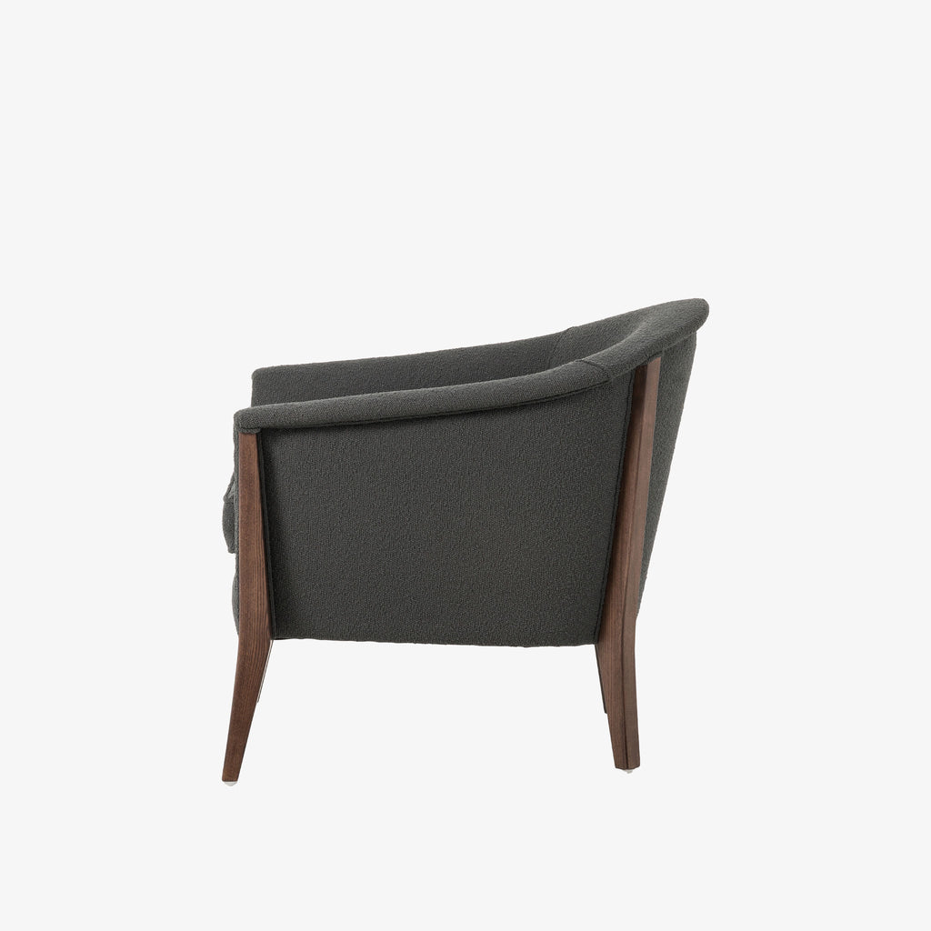 Grey upholstered 'nomad' arm chair by Four Hands Furniture with dark wood frame and rounded back on a white background