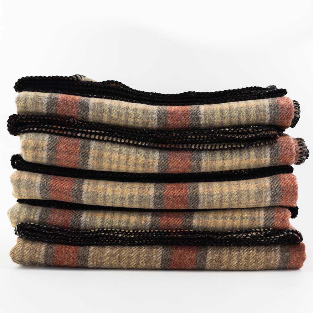 Stack of Johnson Woolen Mills wool blanket in brown, black and beige check print on a white background
