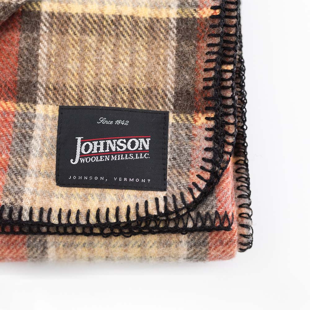 Close up of Johnson Woolen Mills wool blanket in brown, black and beige check print on a white background