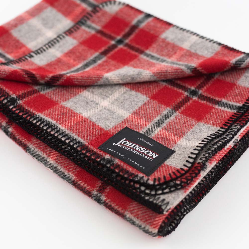 Close up of Johnson Woolen Mills wool blanket in grey and red check print on a white background