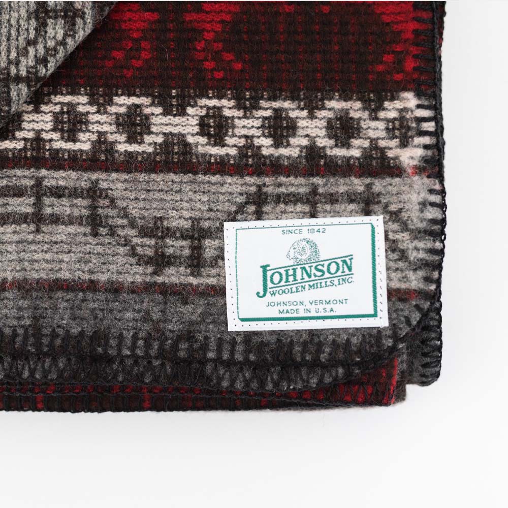 Close up of Johnson Woolen Mills wool blanket in grey and red with holiday reindeer print on a white background