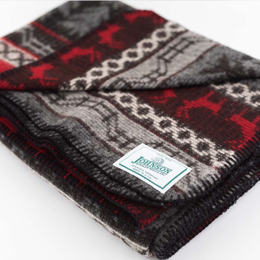 Close up of Johnson Woolen Mills wool blanket in grey and red with holiday reindeer print on a white background