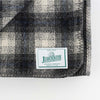 Close up of Johnson Woolen Mills wool blanket in charcoal grey checkered print on a white background