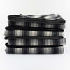Stack of Johnson Woolen Mills wool blanket in charcoal grey checkered print on a white background