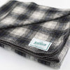 Close up of Johnson Woolen Mills wool blanket in charcoal grey checkered print on a white background
