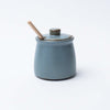 Blue honey pot with wood honey dipper on a white background