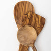 Close up of three olive wood utensil heads on a white background including spatula, large spoon and spoon with round head