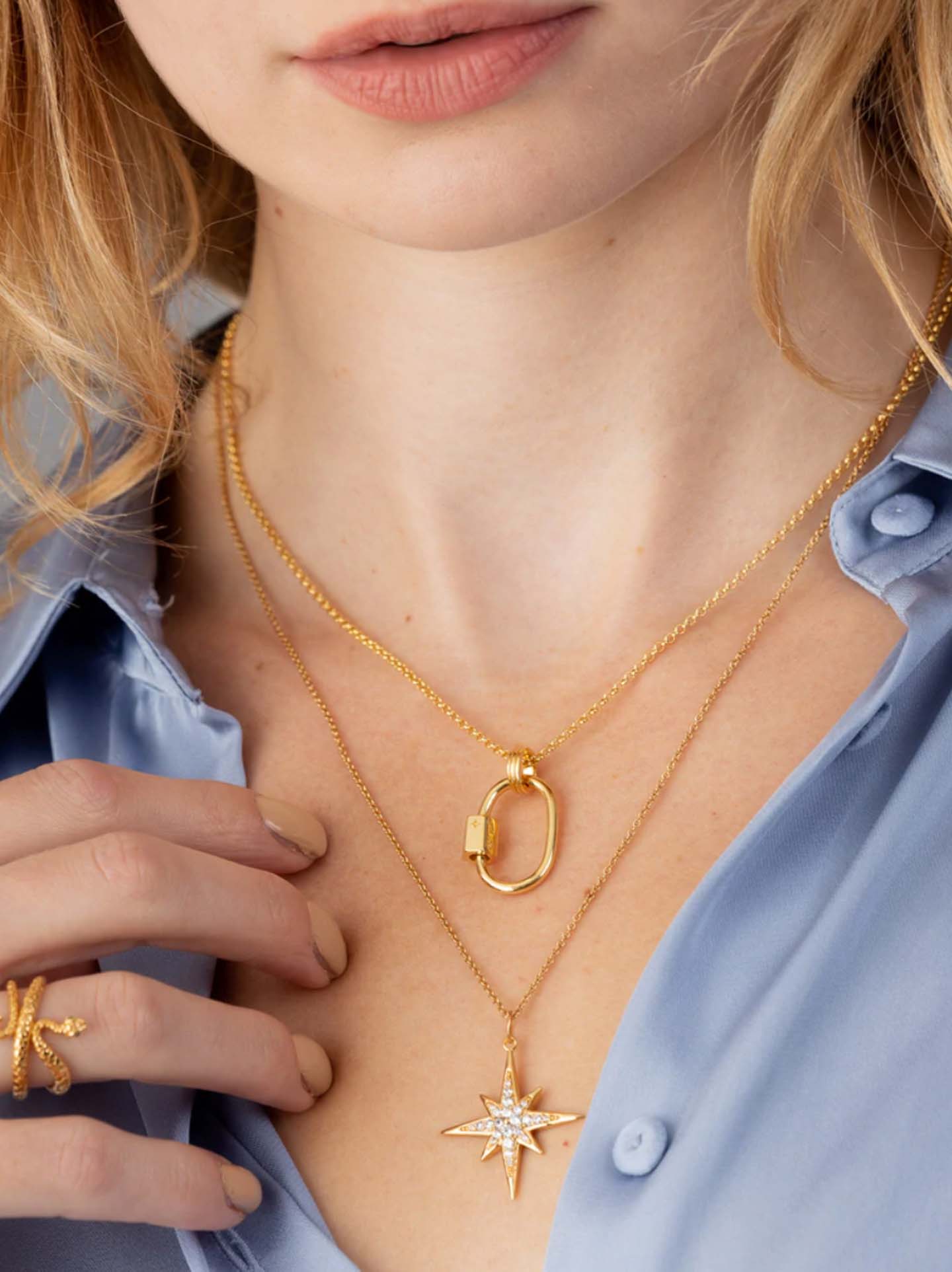 Scream pretty brand carabiner charm necklace in gold on a model with a blue shirt