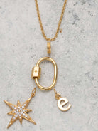 Scream Pretty brand carabiner charm necklace in gold on a stone background with charms