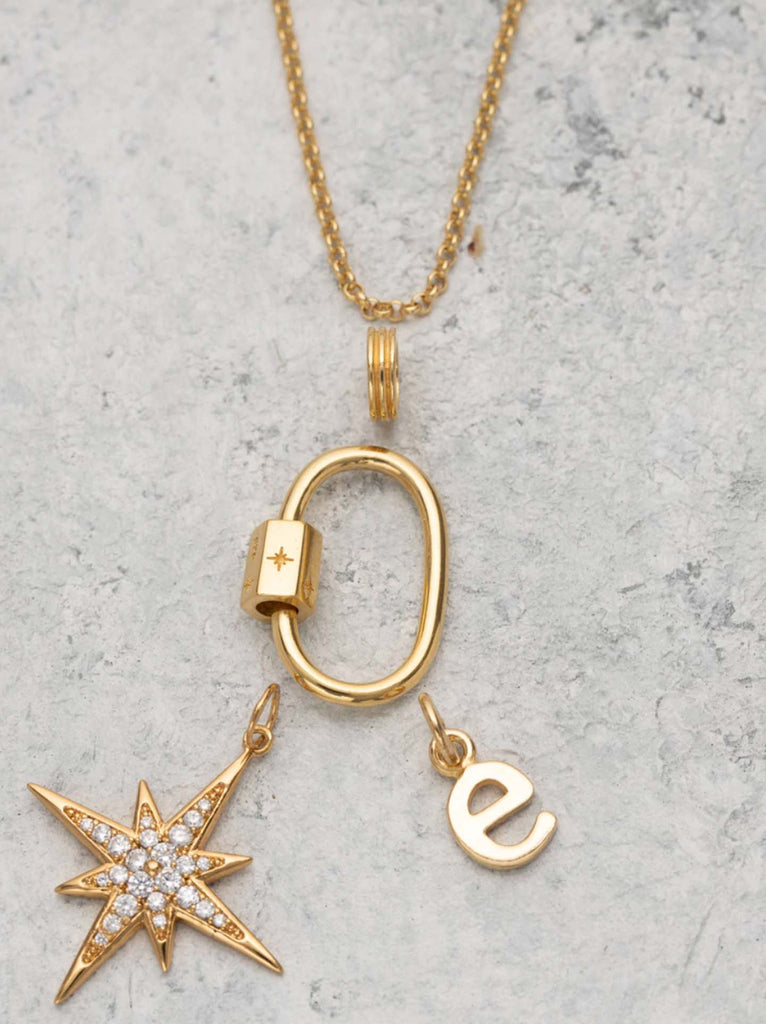 Scream Pretty brand carabiner charm necklace in gold on a stone background with charms