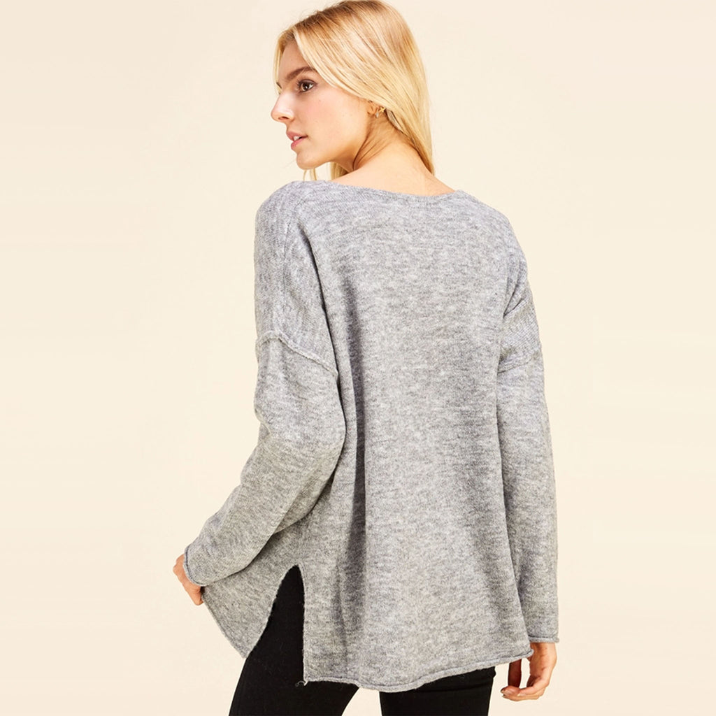Blond Model wearing Pinch brand grey v neck loose fitting sweater with black pants