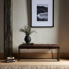 Four hands brand Oxford bench with iron frame and brown leather top in an entryway with books and black and white photo above
