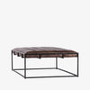Four hands brand Oxford rectangular coffee table with black iron frame frame and distressed brown leather top on a white background