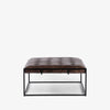 Four hands brand Oxford rectangular coffee table with black iron frame frame and distressed brown leather top on a white background