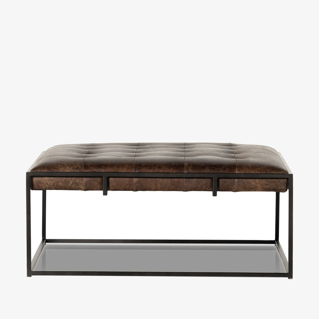 Four hands brand Oxford square coffee table with black iron frame frame and distressed brown leather top on a white background