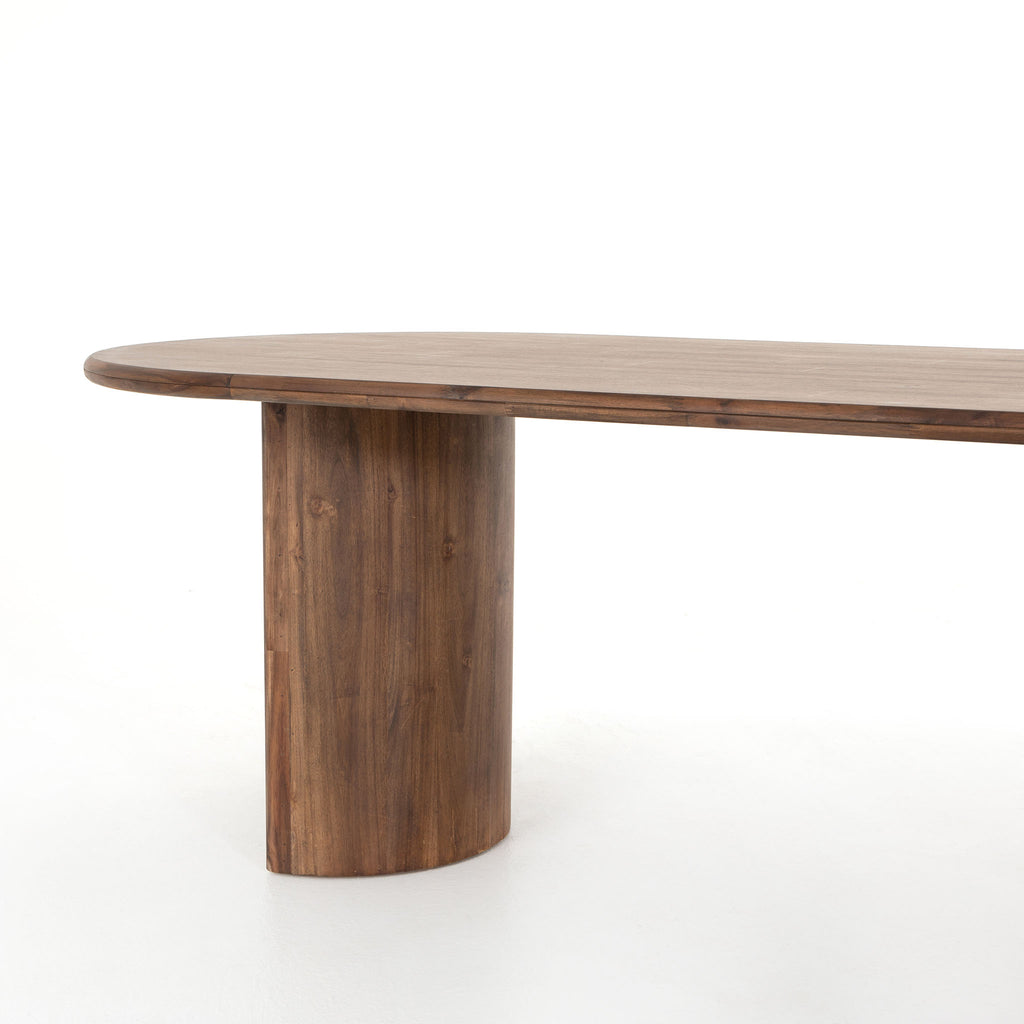 Seasoned dark wood 'Paden' oval dining table by Four Hands Furniture with two legs to support thick top on a white background