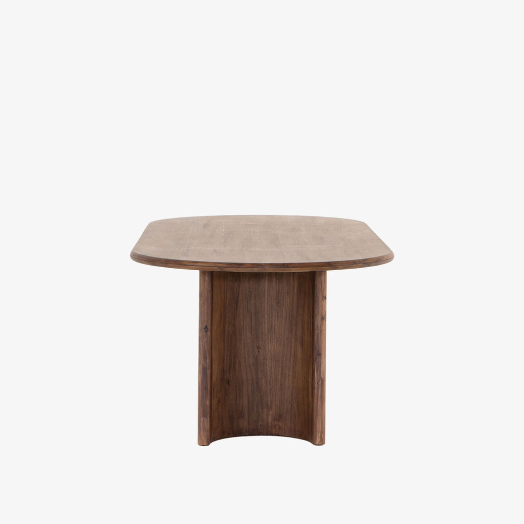 Seasoned dark wood 'Paden' oval dining table by Four Hands Furniture with two legs to support thick top on a white background