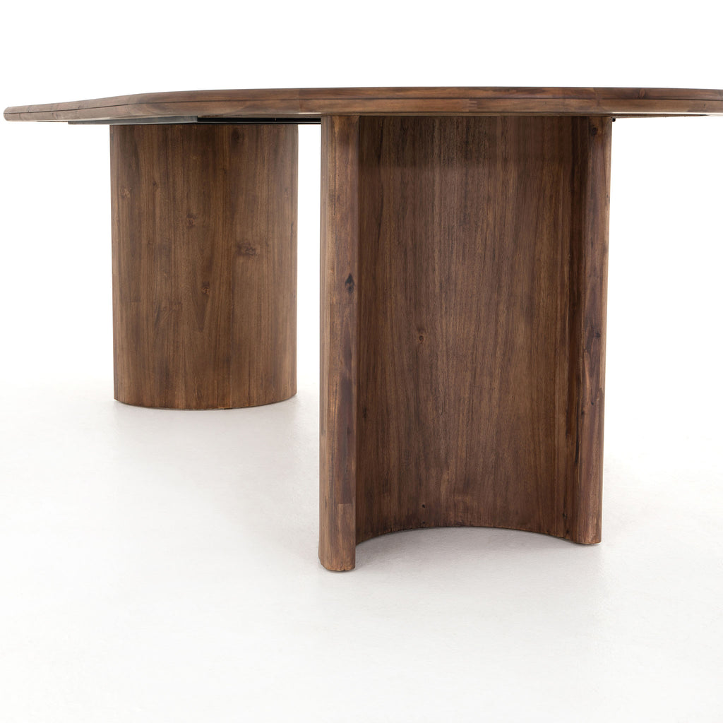 Seasoned dark wood 'Paden' oval dining table by Four Hands Furniture with two legs to support thick top on a white background