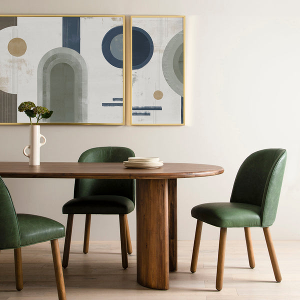 Seasoned dark wood 'Paden' oval dining table by Four Hands Furniture with two legs to support thick top in a dining room with green dining chairs