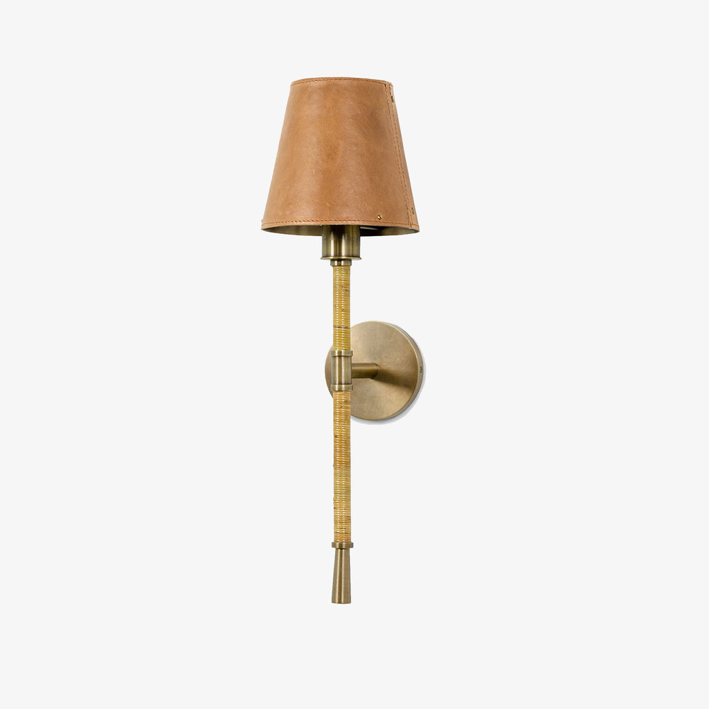 Palecek Hendrick Sconce with leather shade and rattan wrapped brass arm on a white background