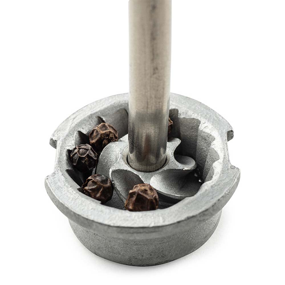 Close up of pepper grinding mechanism of Peugeot Paris brand stainless pepper mill on white background