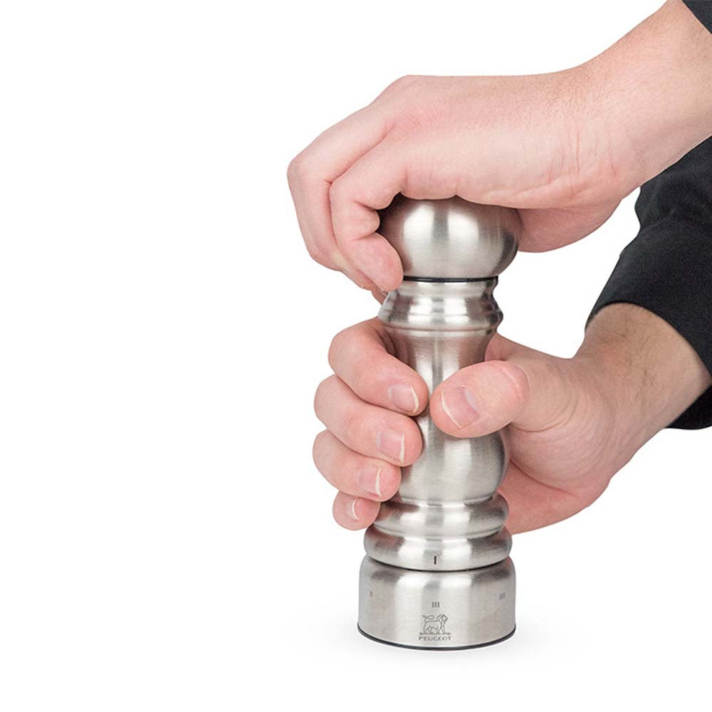 Hands turning Peugeot Paris brand stainless 7 inch mill on white background