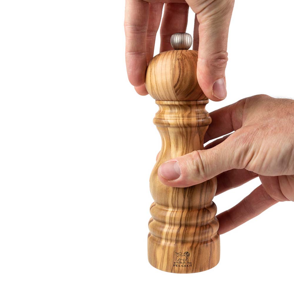 Hand grinding Peugeot Paris brand olive wood mill on a white background