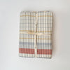 Off white tablecloth with blue, yellow and red plaid pattern tied with ribbon on a white background