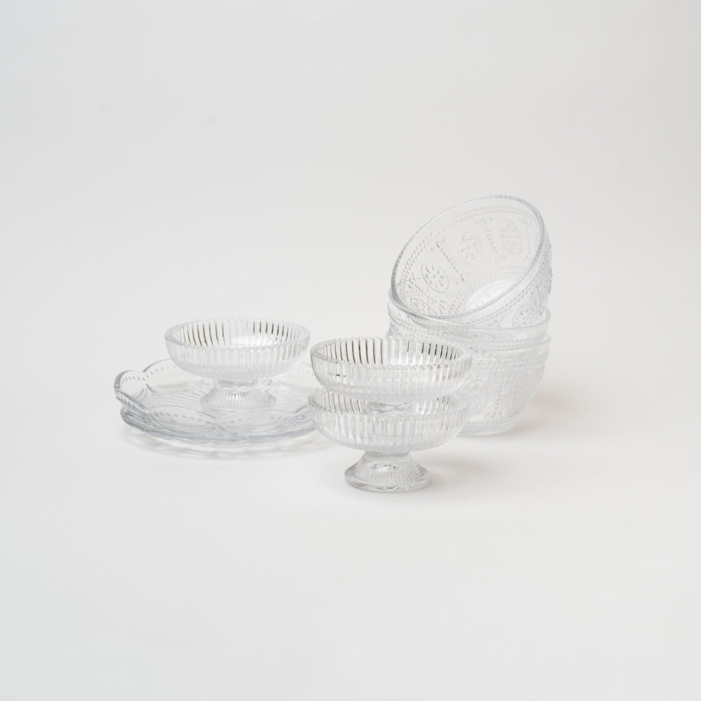 Collection of pressed glass plates and bowls on a white background