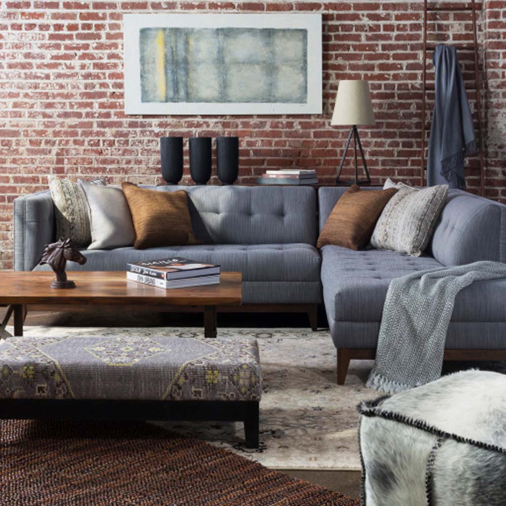 Living room with Brock wall and grey sofa with cowhide ottoman in the foreground
