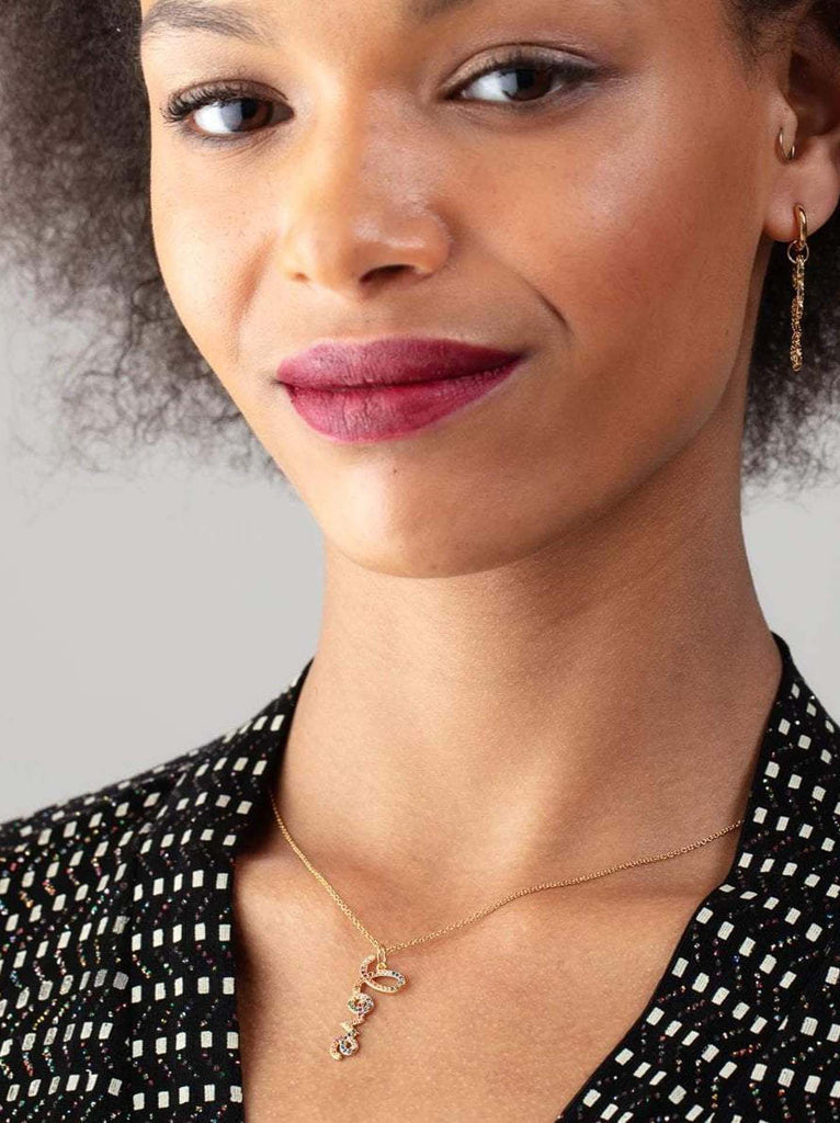 Scream Pretty brand love charm with rainbow colored stones on a model with black and white blouse